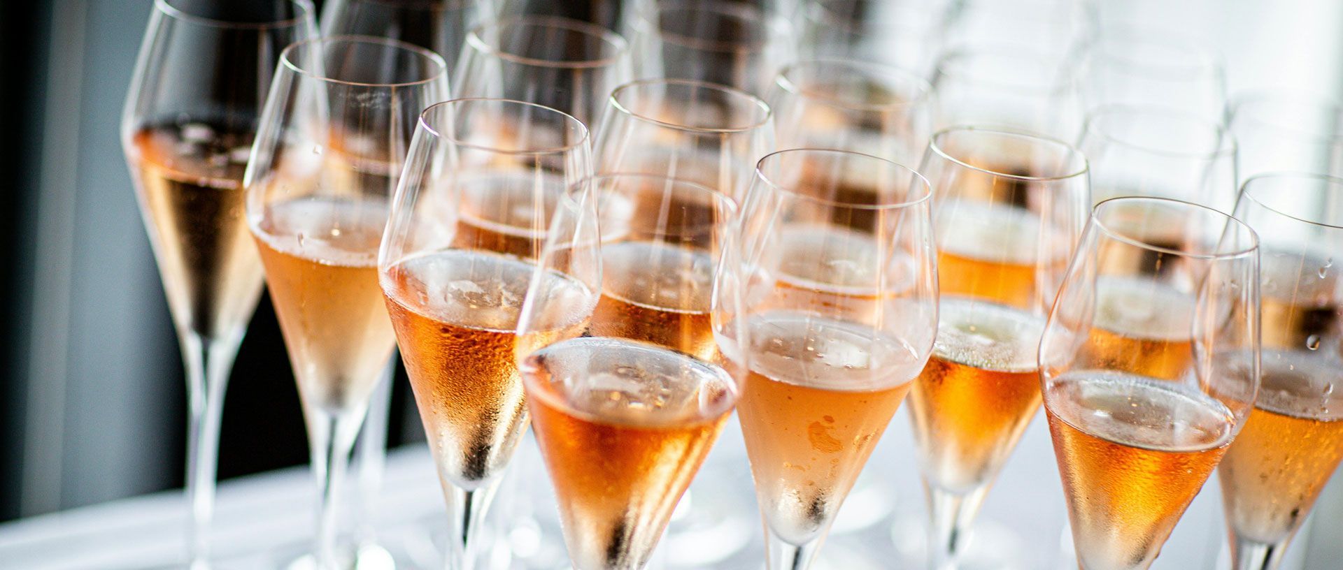 Rows of champagne flutes filled with sparkling rosé, arranged on a table