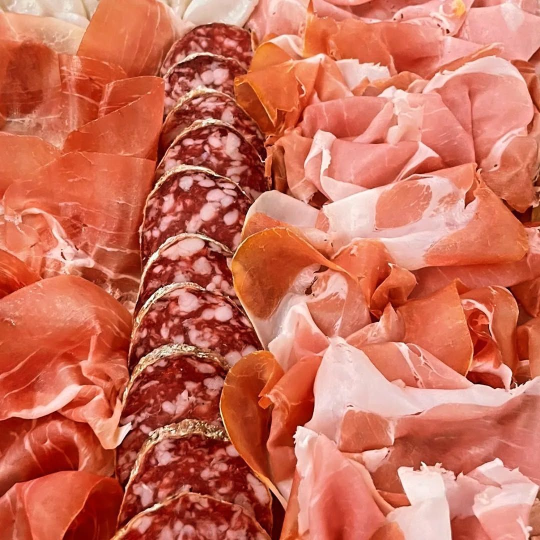 Scaffali per vino e articoli da regalo in una corsia di un negozio, riforniti di bottiglie, snack e prodotti confezionati.