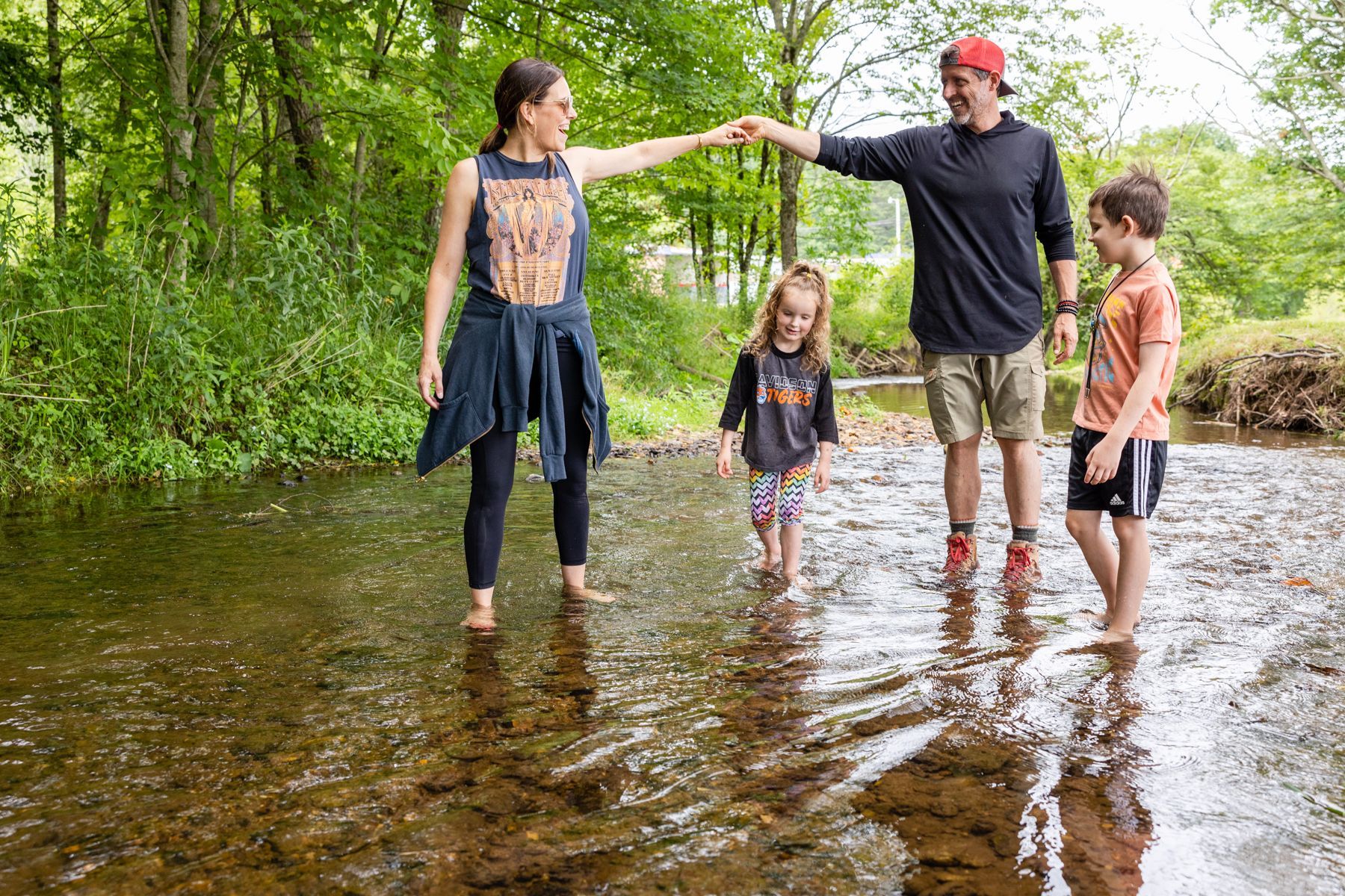 A family is standing in a stream holding hands.