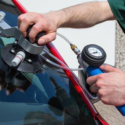 Person repairing windshield crack with special tools.