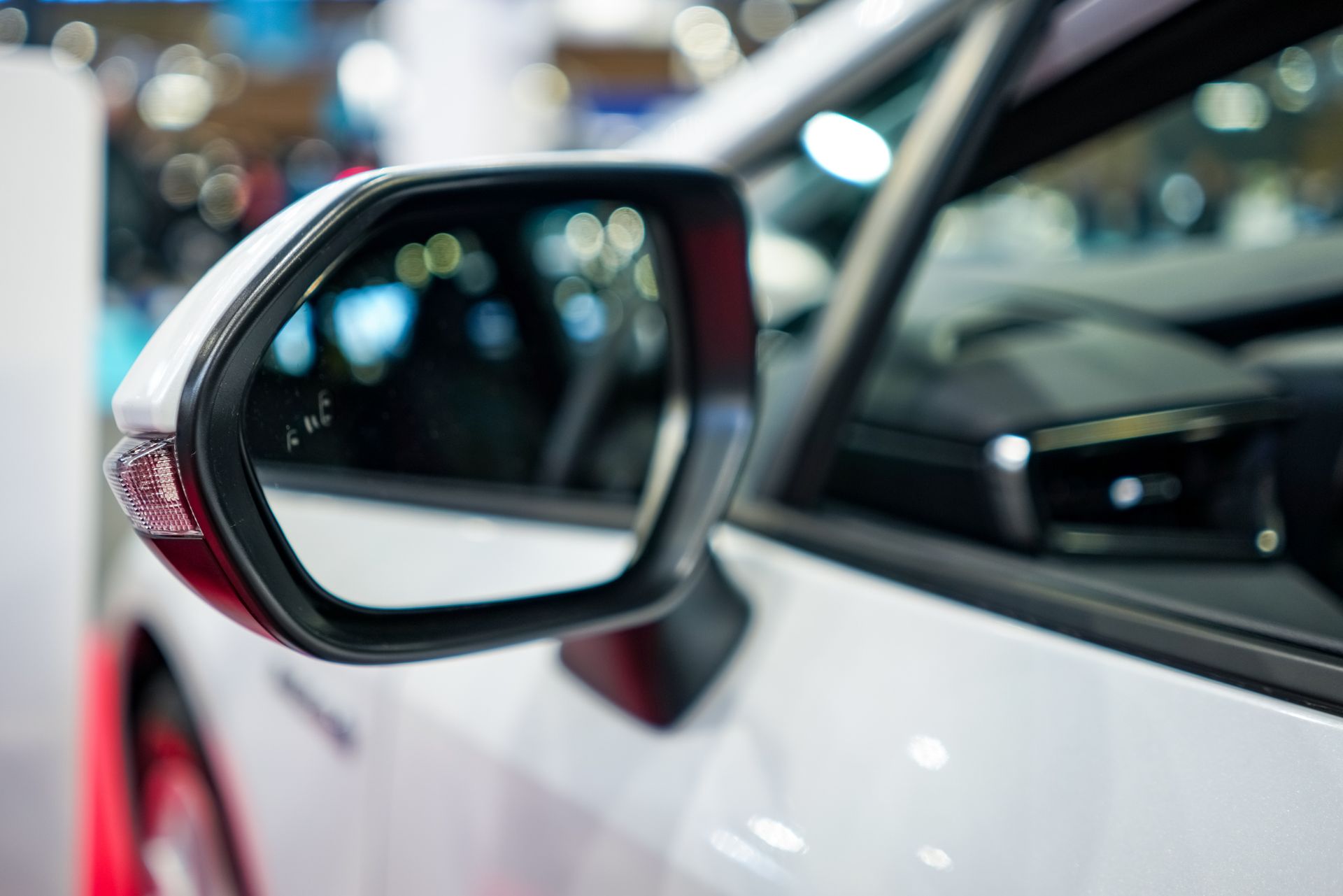 White car side mirror, showing blurred background of interior and exterior.