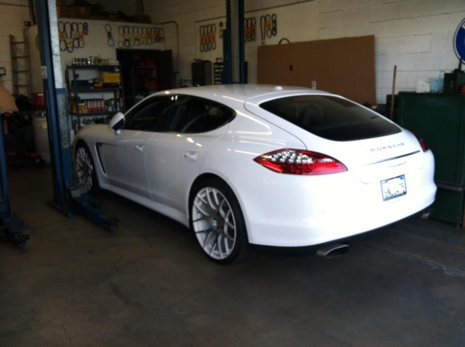 White Porsche Panamera on a car lift in an auto repair shop.