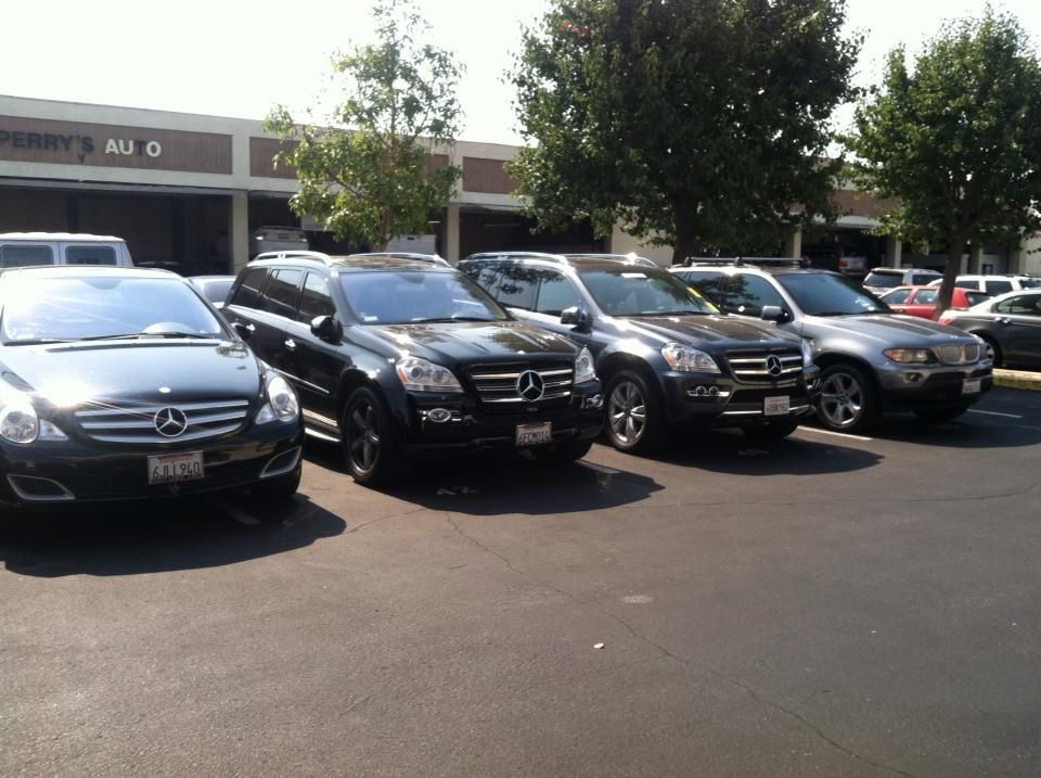 Row of black SUVs parked in front of a strip mall on a sunny day.