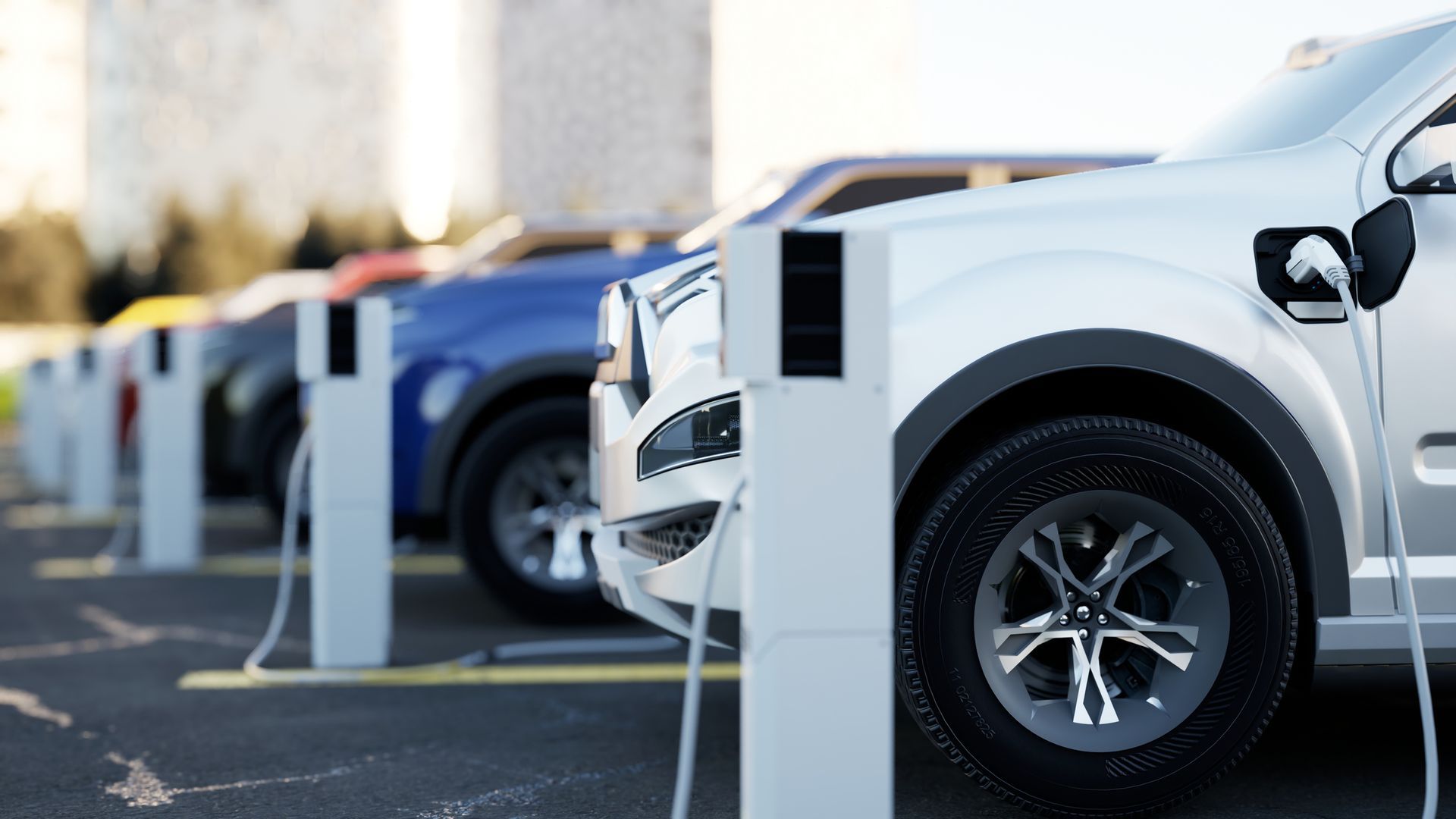 Electric vehicles charging at a station. Silver, blue, and black cars are connected to charging cables. Electric vehicles charging at a station. Silver, blue, and black cars are connected to charging cables.