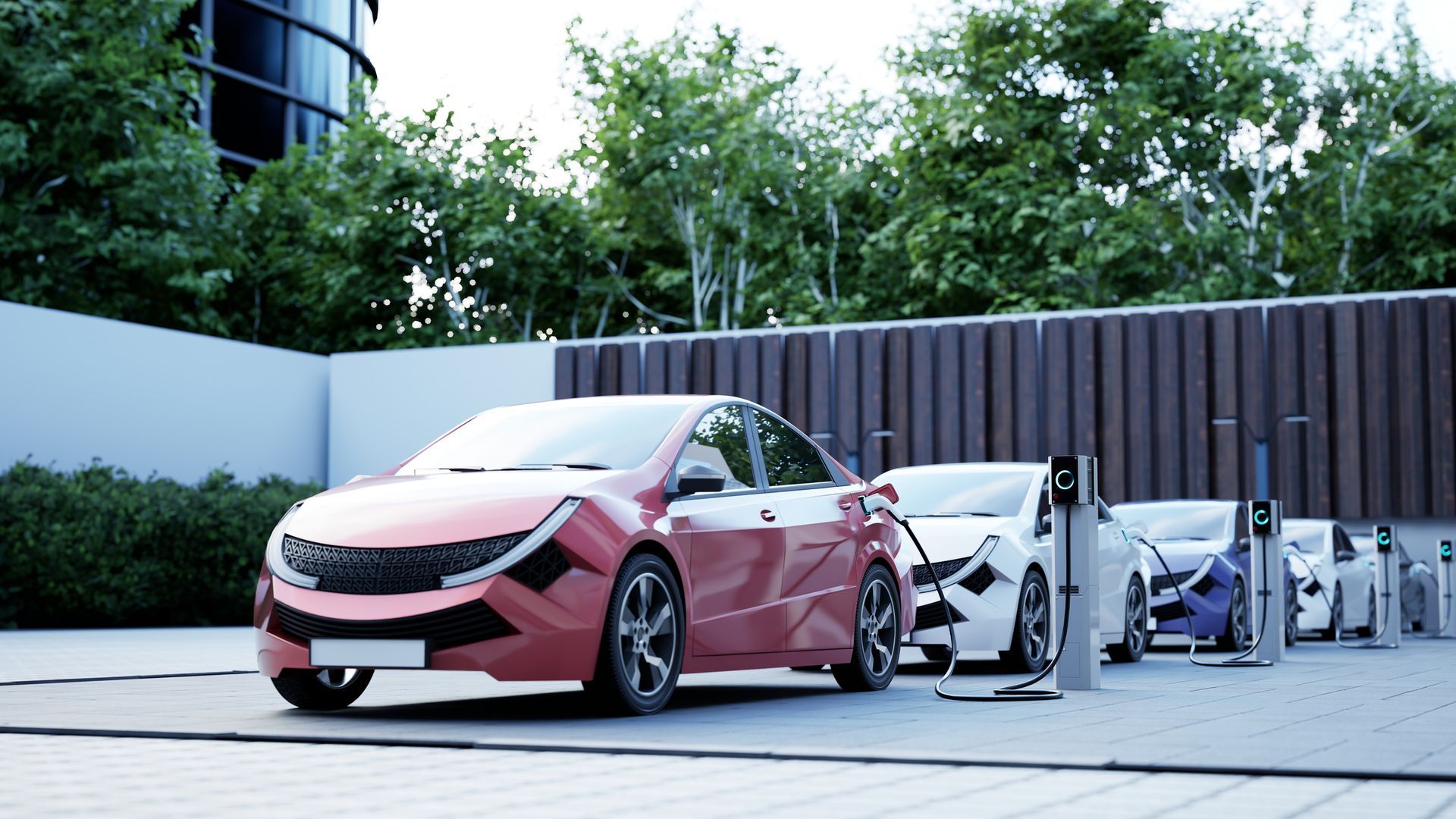 Electric cars charging in a row, with a red car in front. Lush greenery and modern building in the background. Electric cars charging in a row, with a red car in front. Lush greenery and modern building in the background.