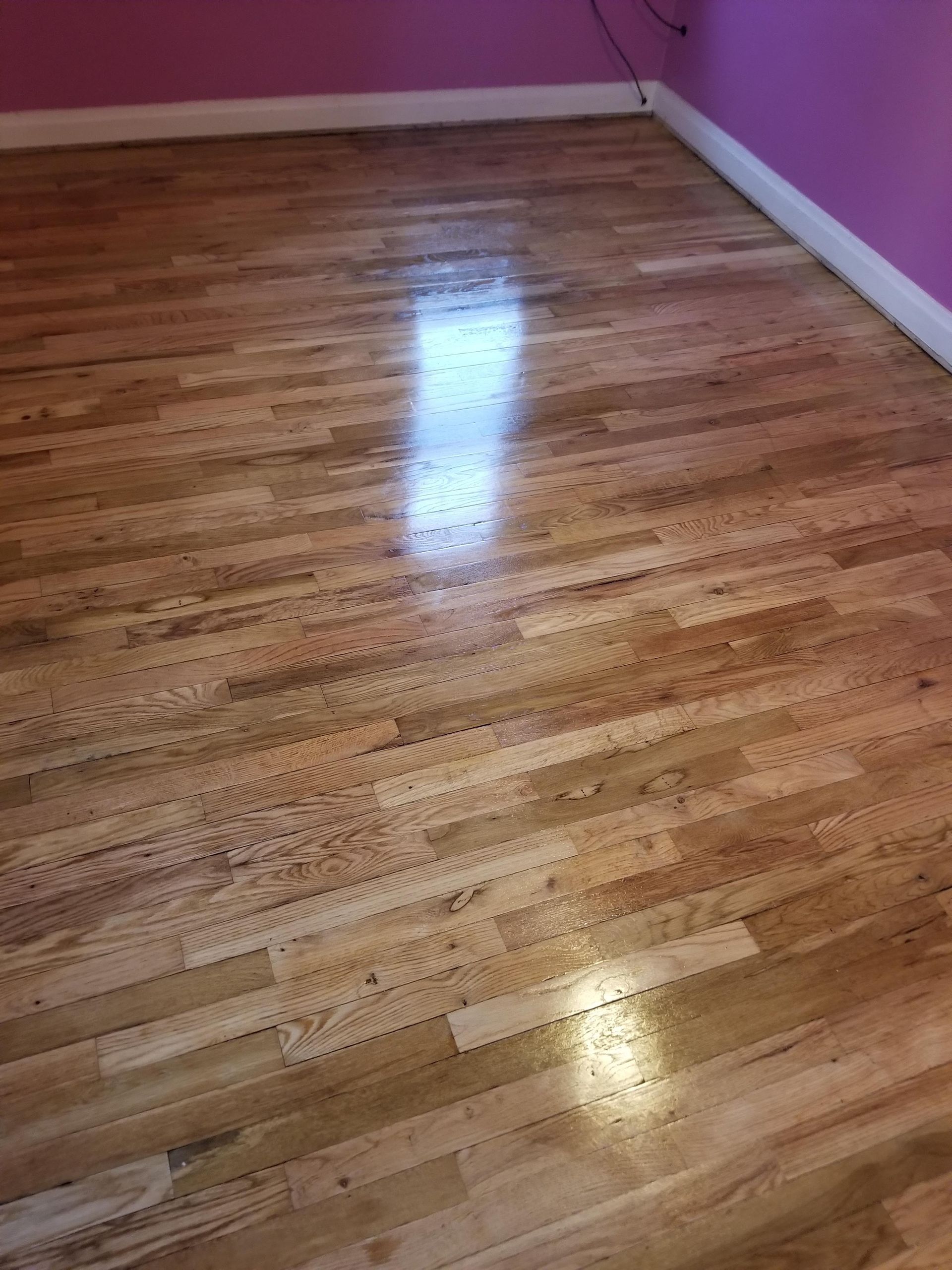 A wooden floor in a room with pink walls.