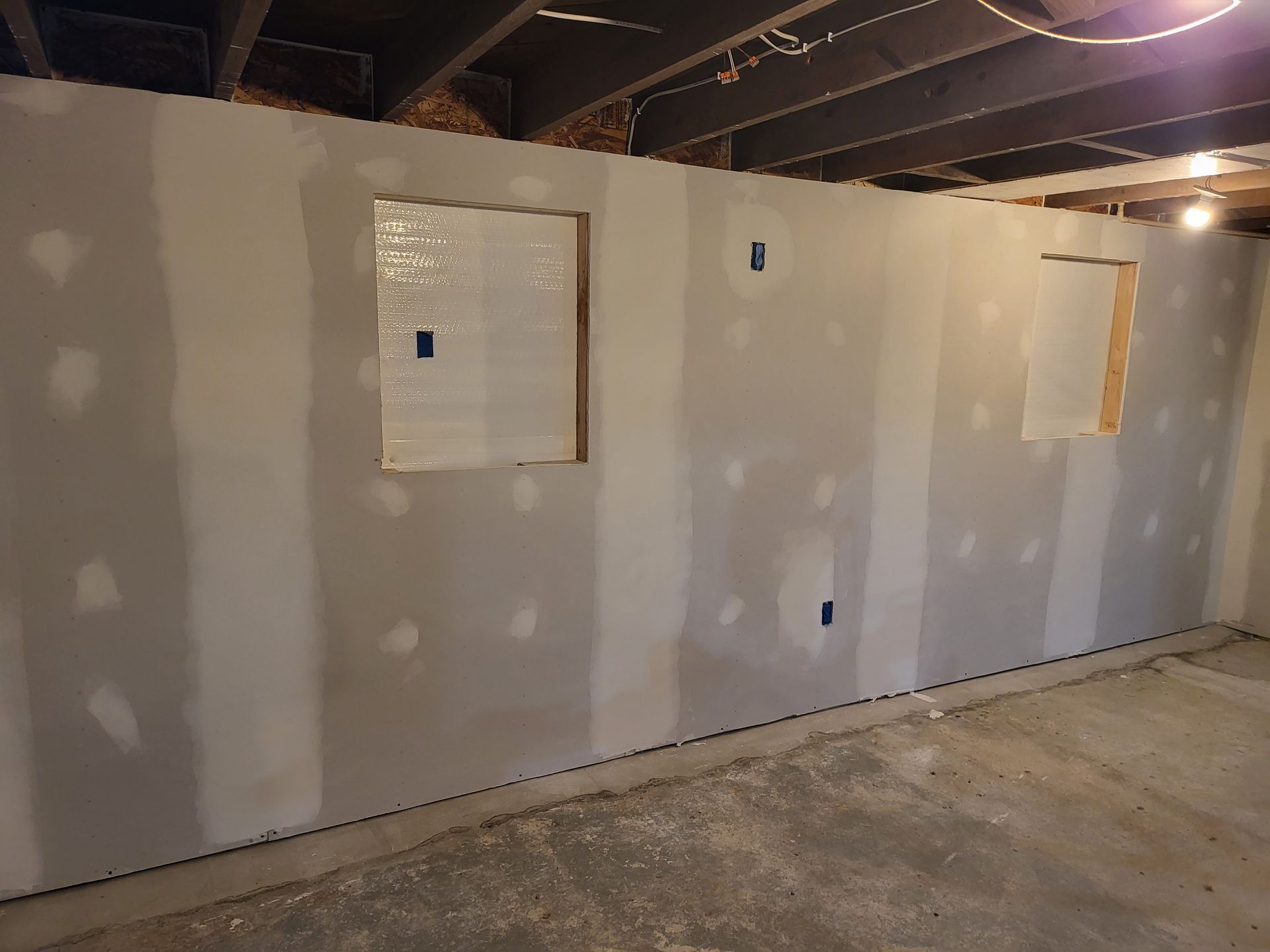 A basement with drywall walls and a window.