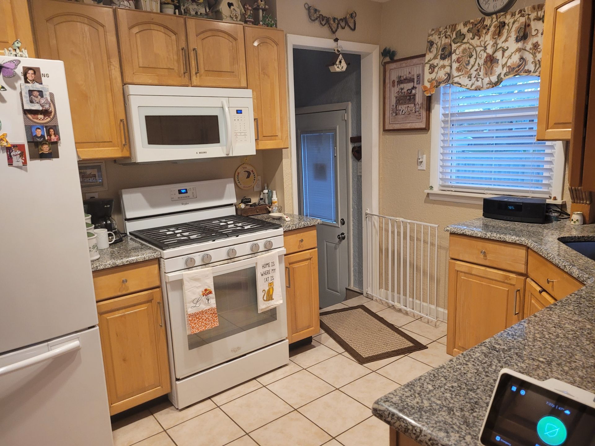 A kitchen with a stove , microwave , refrigerator and cabinets.
