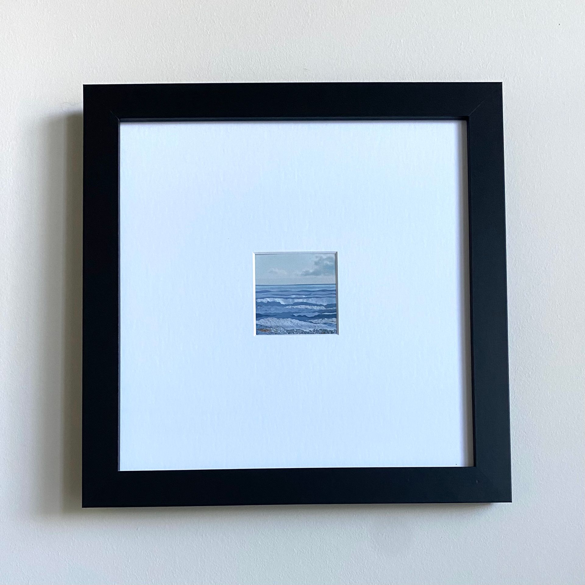 Blue and white landscape of ocean waves under a cloudy sky.