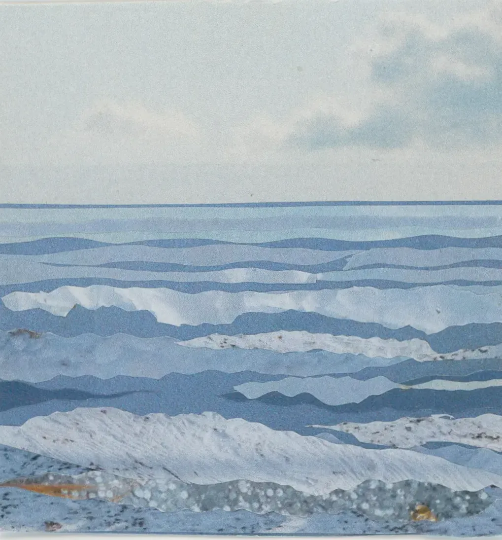 Blue and white landscape of ocean waves under a cloudy sky.