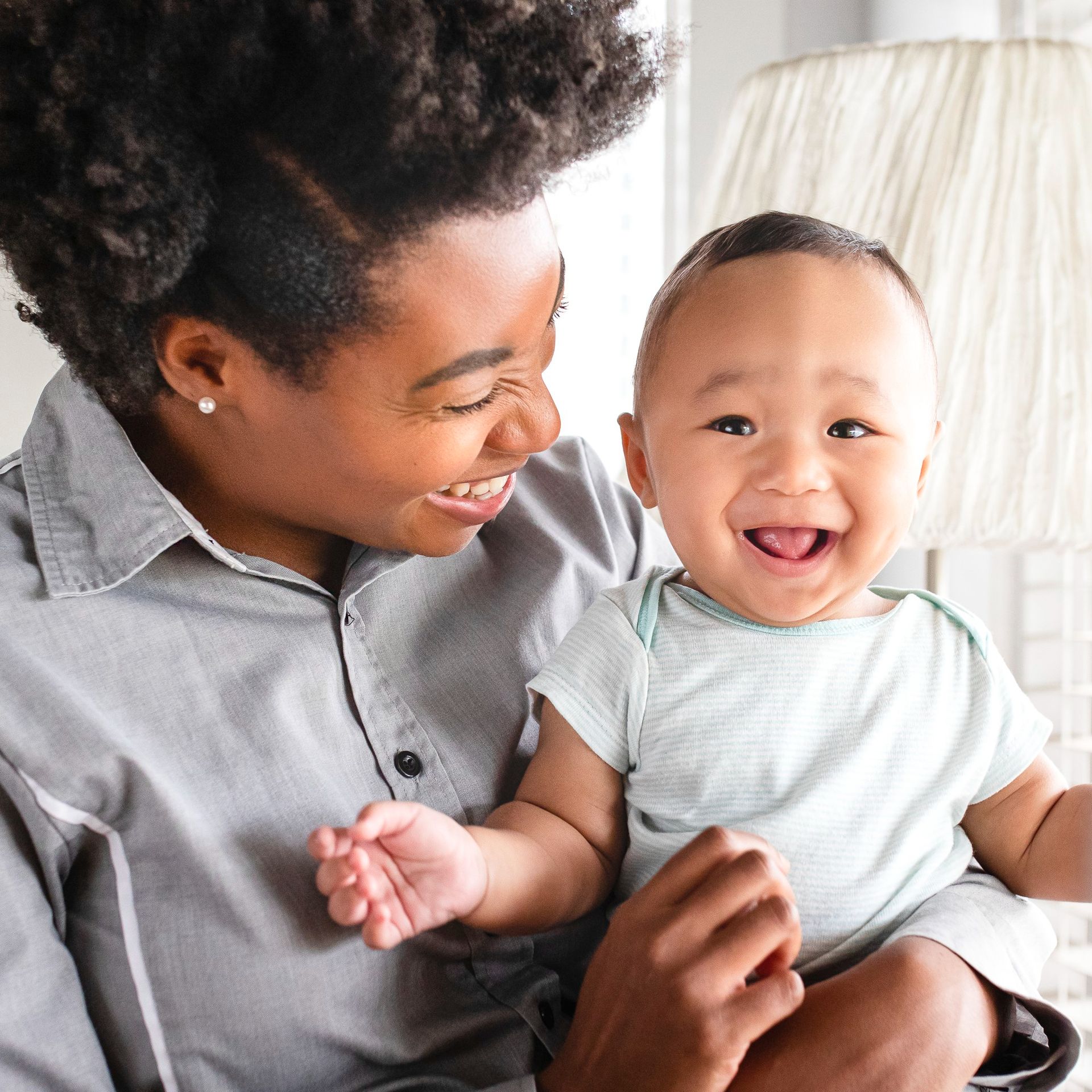 A woman is holding a baby in her arms and the baby is smiling.