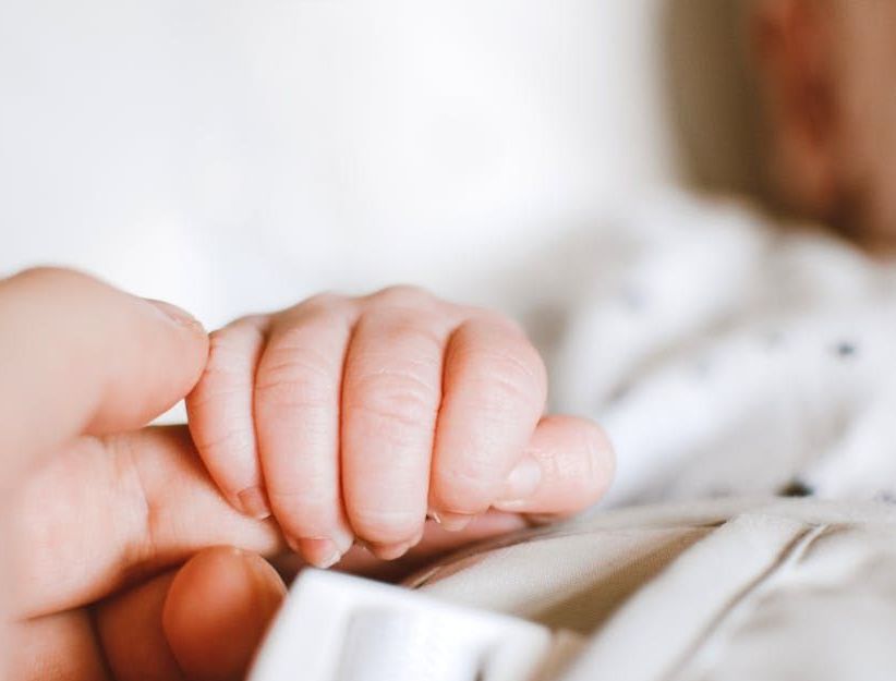 A close up of a person holding a baby 's hand.