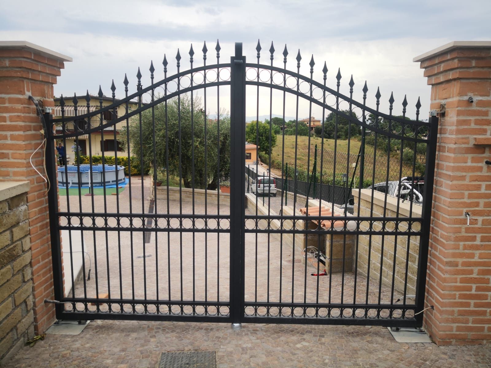 Un cancello nero con un muro di mattoni dietro