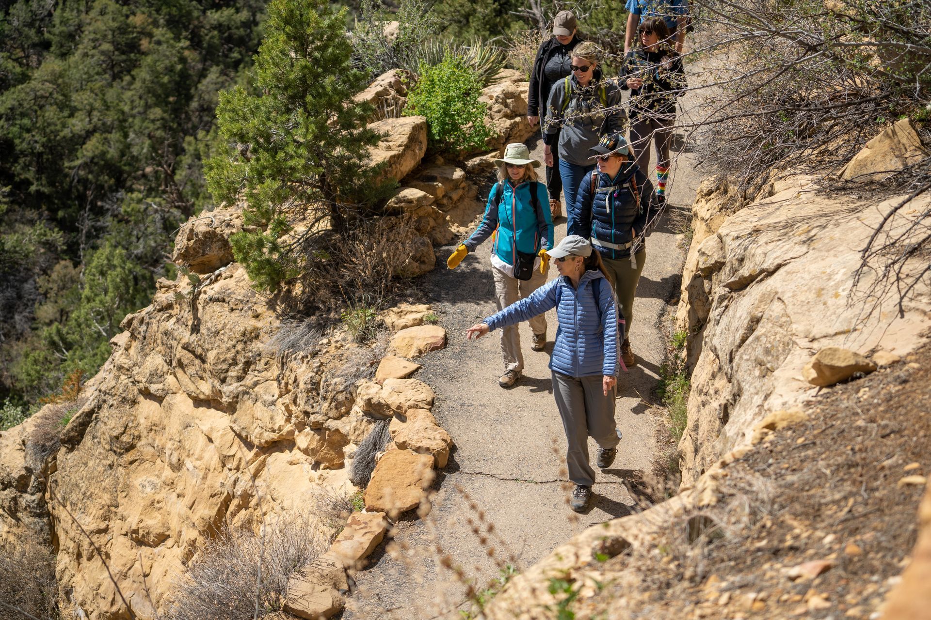 A group of people are hiking down a trail in the mountains.