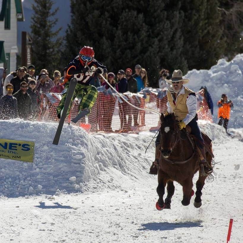 A man is riding a horse in the snow near a sign that says ne 's