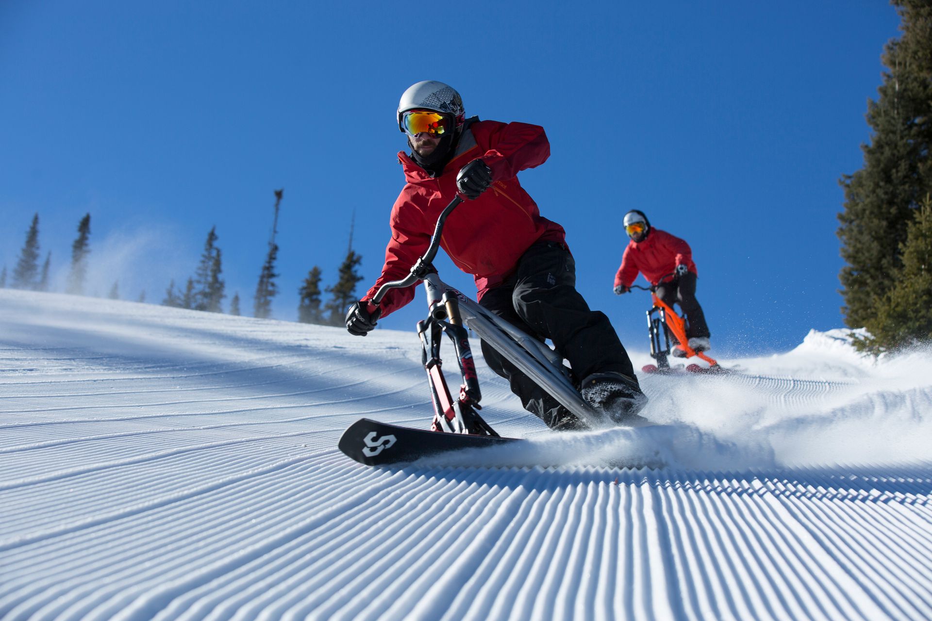 A person is skiing down a snow covered slope on a snow bike.