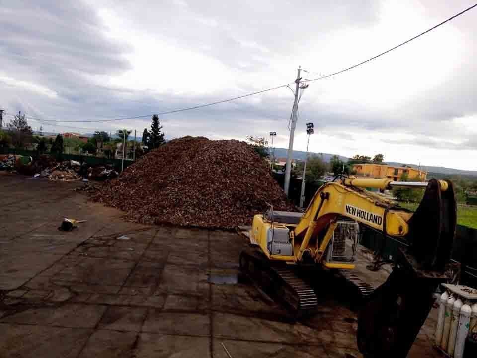 accumuli di rottami ferrosi e macchina operatrice gialla