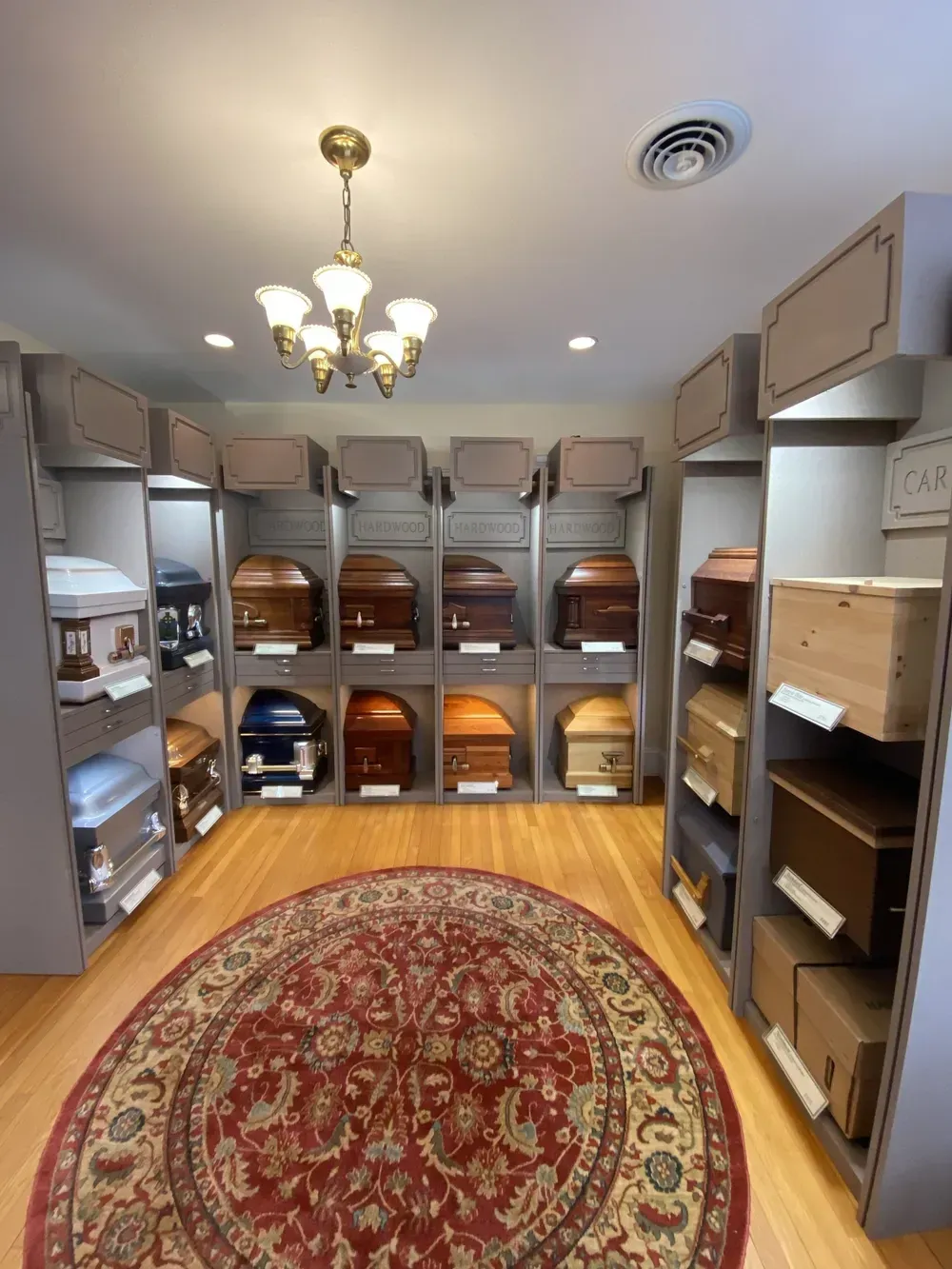 Walk-in closet with gray shelving, hanging clothes, wicker baskets, and a red oval rug on wood floor.