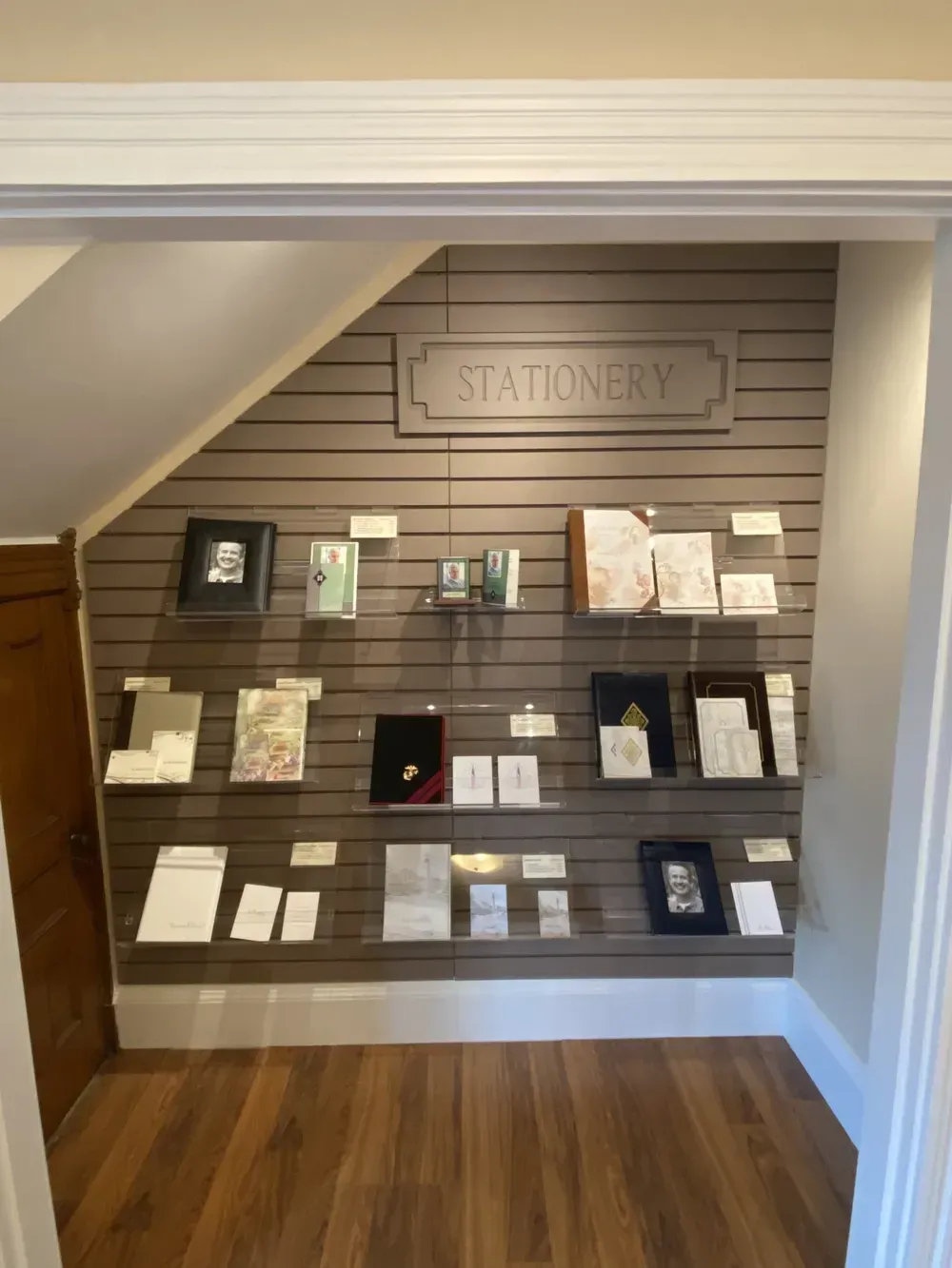 Stationery display wall with cards and notebooks on shelves in a wood-floored alcove