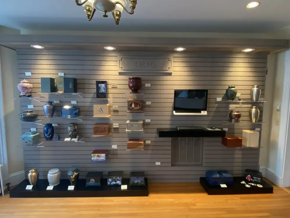 Wall display of assorted glassware and decor on shelves in a showroom, with a TV and marble accent panel.