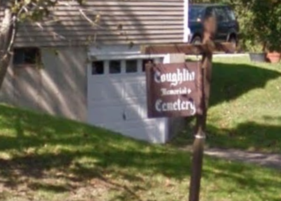 Brown roadside sign reading “Country Cottages” near a driveway and house lawn.