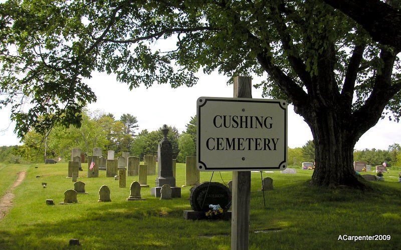 Cushing Cemetery sign in a grassy cemetery with tombstones and large trees