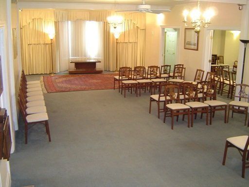 Empty meeting room with chairs arranged around a carpeted floor and a small stage at the front