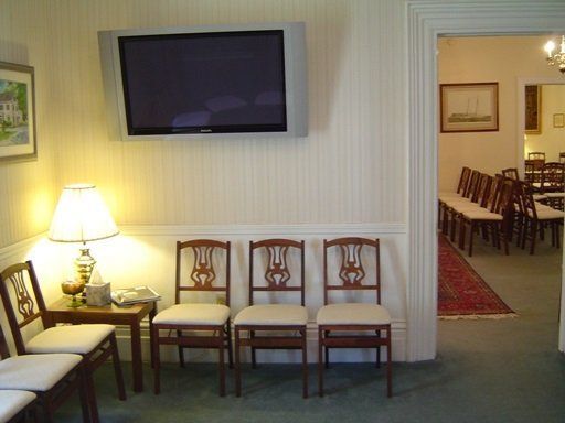 Cozy living room with wall-mounted TV, chairs, lamp, and doorway to dining room