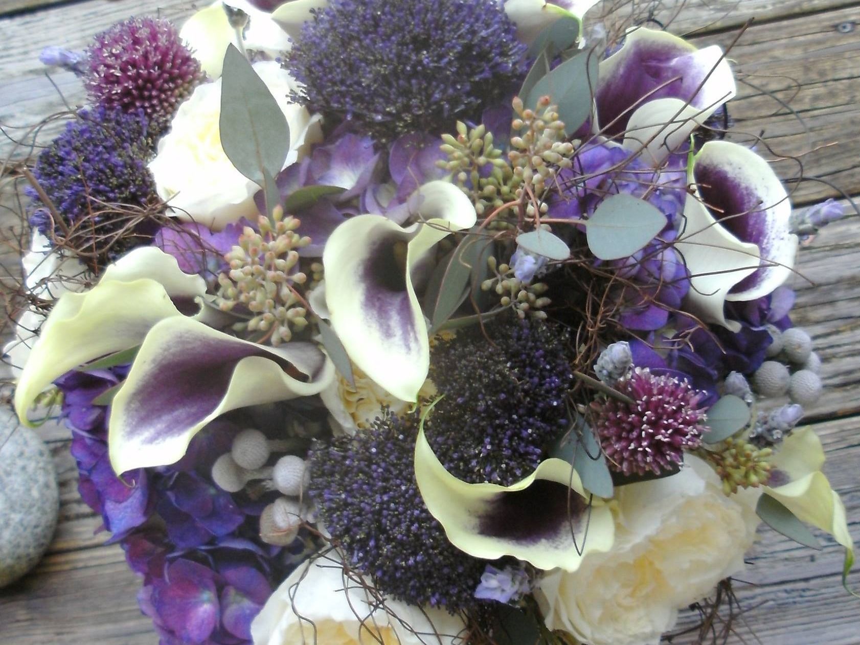 Purple and cream floral bouquet with calla lilies and berries on weathered wood