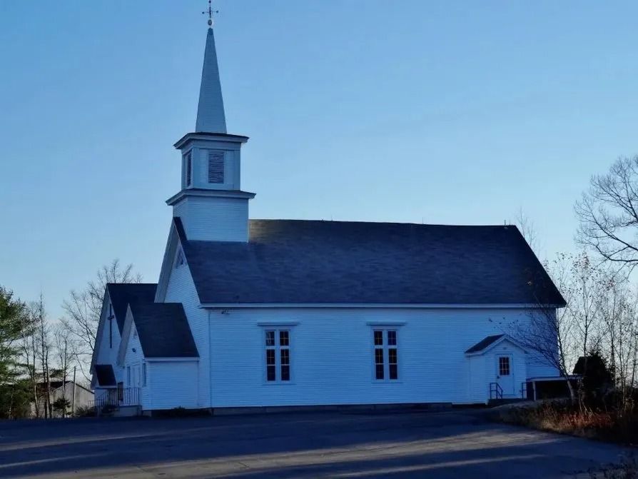 White church with tall steeple at dusk under a blue sky
