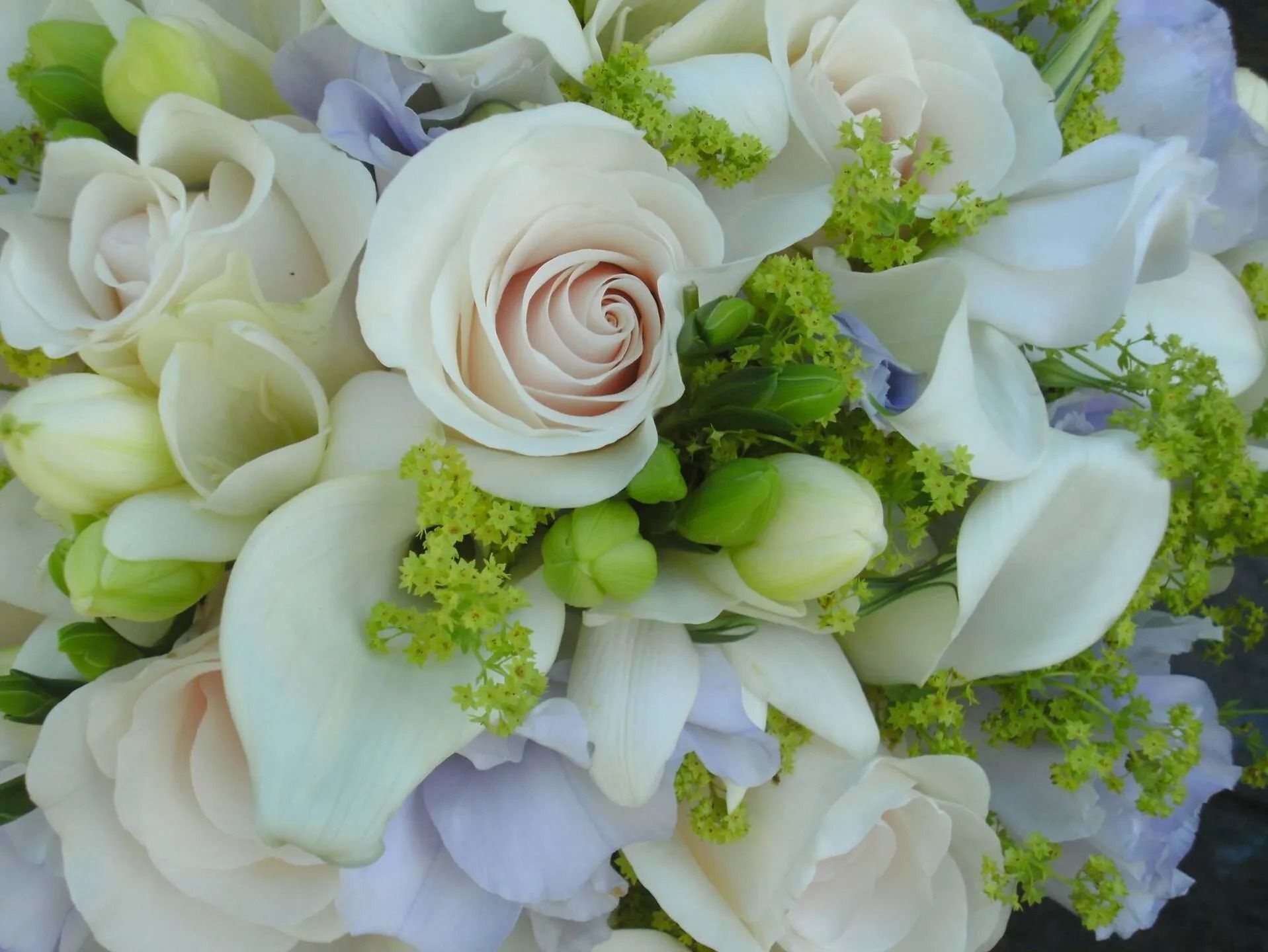 White and pale lavender roses with green filler flowers in a soft bouquet