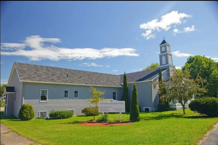 White church with a steeple on a sunny day, set on a green lawn under a blue sky