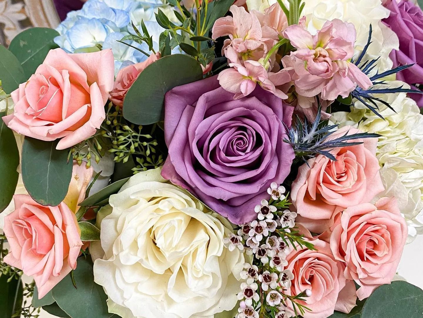 Assorted pastel roses and flowers in pink, lavender, cream, and white bouquet