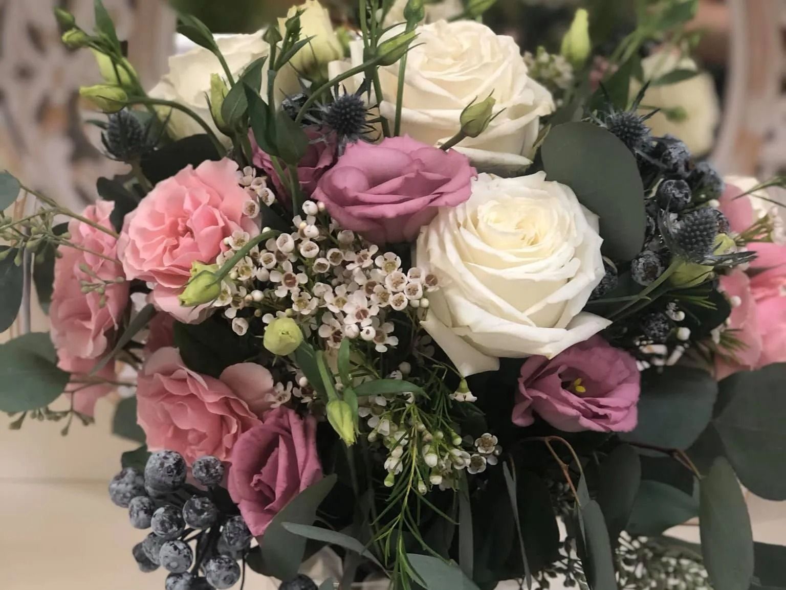 Mixed bouquet of white, pink, and mauve roses with greenery and small filler flowers