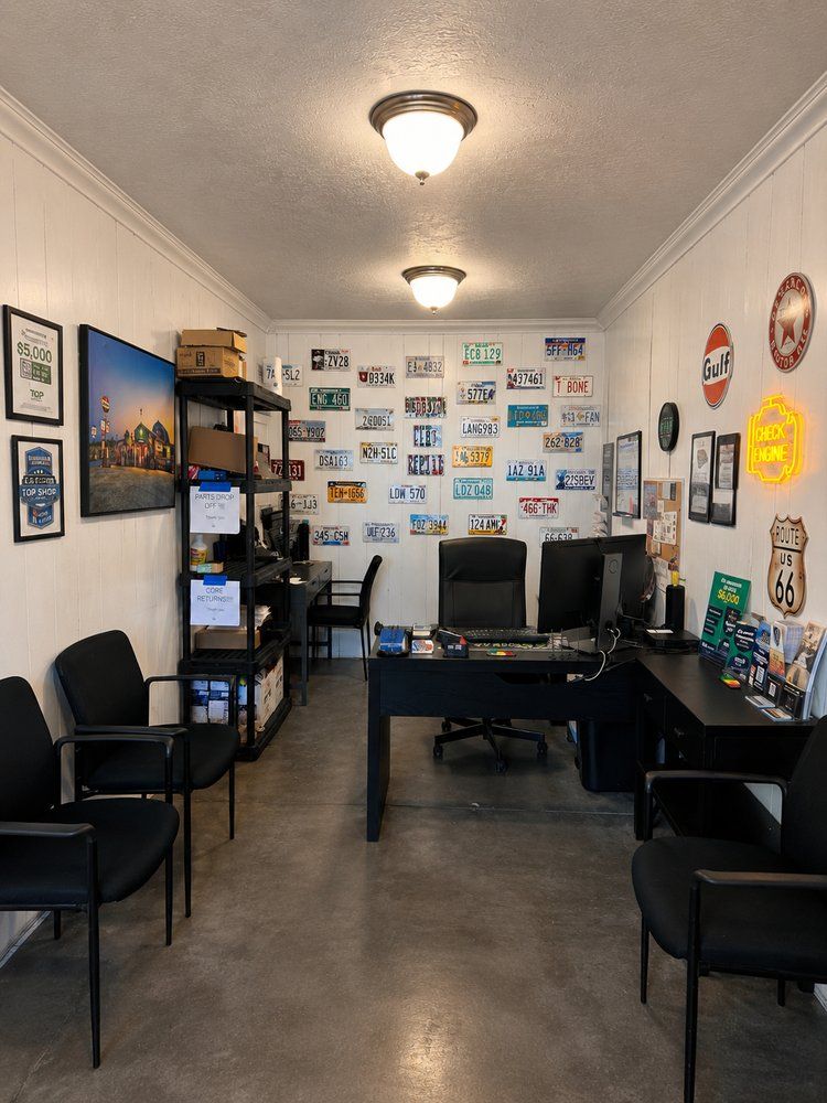 Small office with desks, computers, black chairs, wall art, and a concrete floor | Perryman Auto Repair