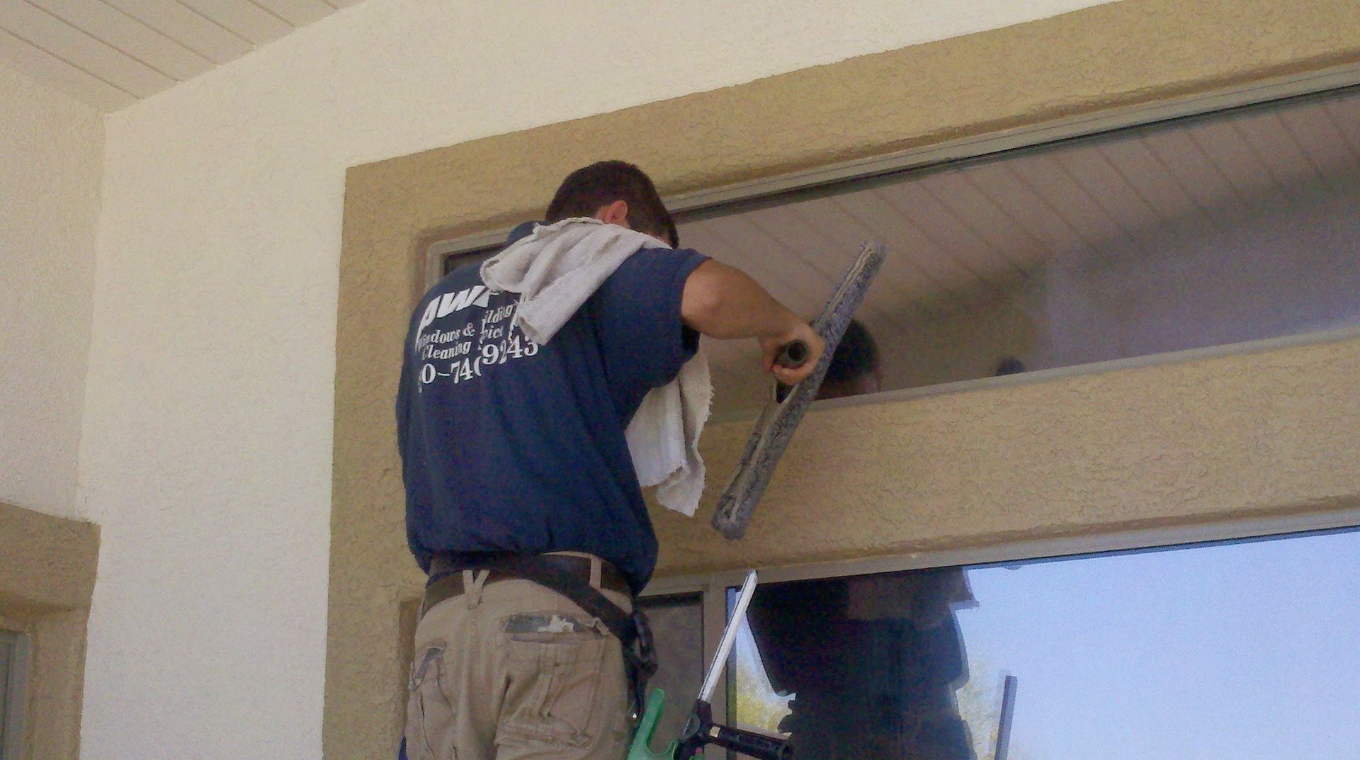 Worker installing a garage door opener on a ladder near the ceiling.
