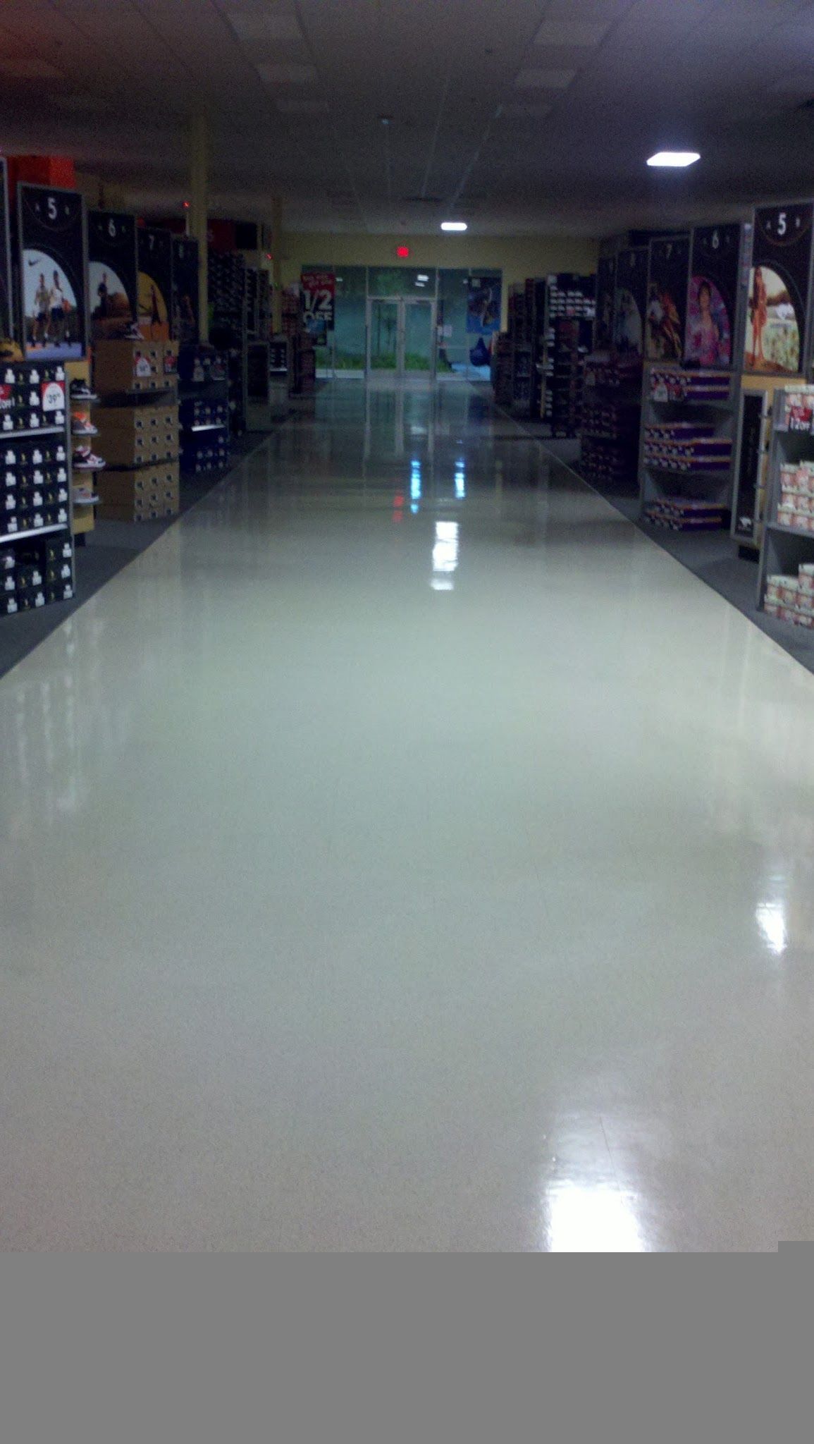 Gloved hand applying sealant along a floor tile seam with a caulking tool