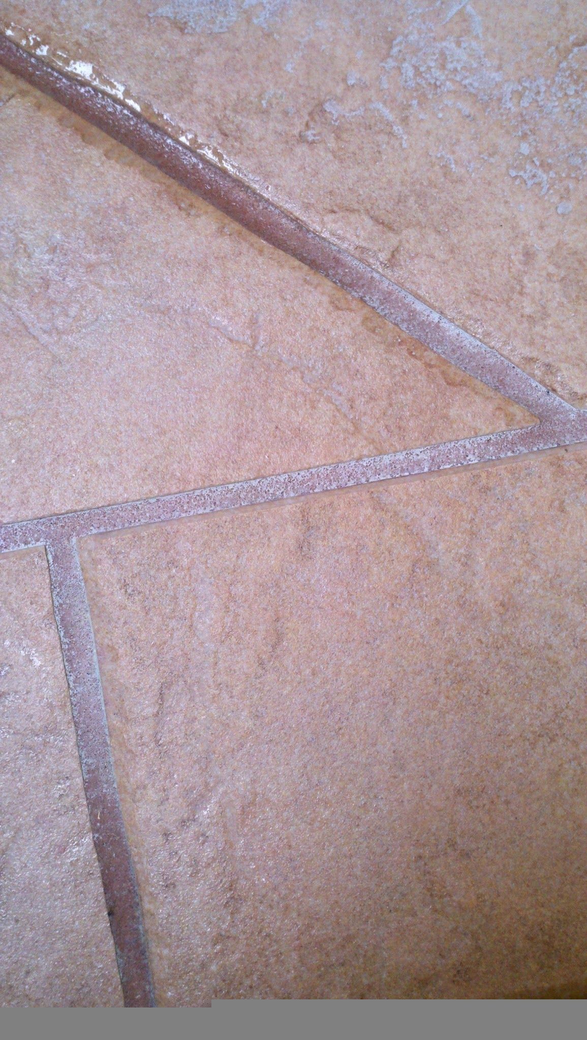 Close-up of a tan tiled floor with gray grout lines forming angular shapes.