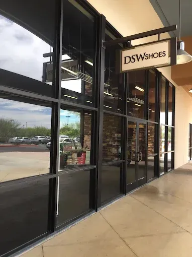 Storefront sidewalk outside DSW shoes, with large glass windows and an illuminated sign.