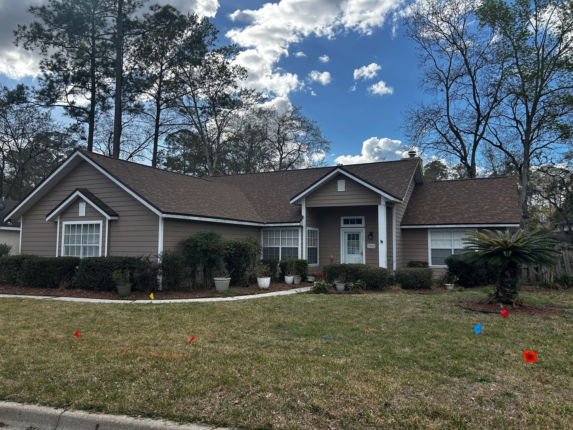 Brown house with a dark roof and white trim, set in a grassy yard under a blue sky. Brown house with a dark roof and white trim, set in a grassy yard under a blue sky.