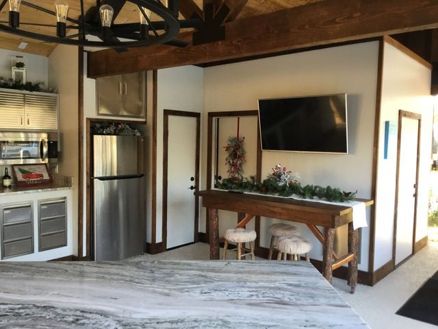 Cozy kitchen nook with a stainless fridge, wall TV, and wooden table in a rustic interior