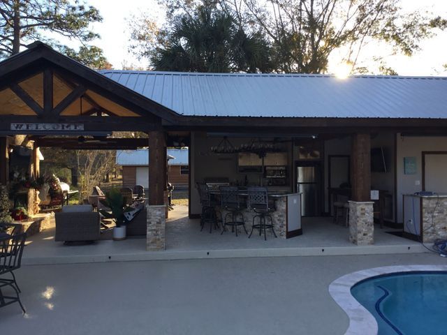 Outdoor patio with a covered bar area and seating beside a swimming pool at sunset