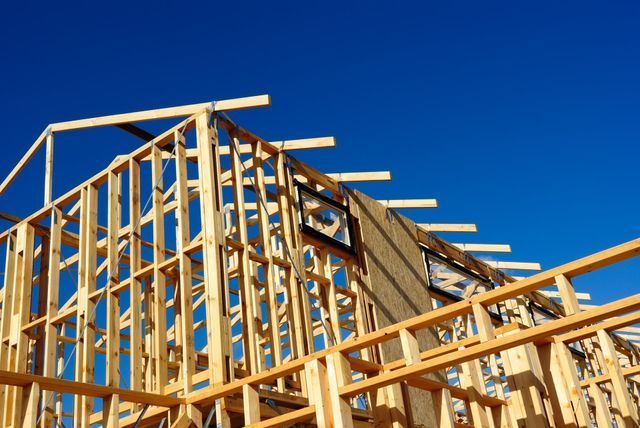 Wood framing of a house under construction against a clear blue sky