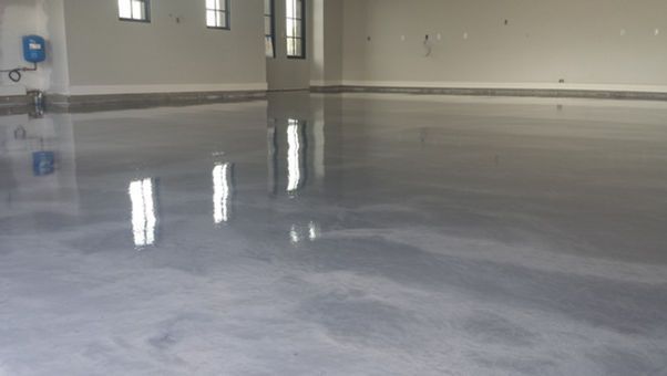 Empty polished concrete room with reflective floor and small windows along the wall