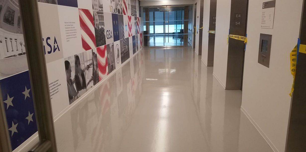 Bright hallway with glossy floors, wall murals, and glass doors at the end
