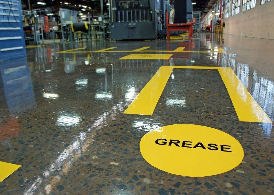 Industrial floor with yellow grease warning marking on a shiny factory surface
