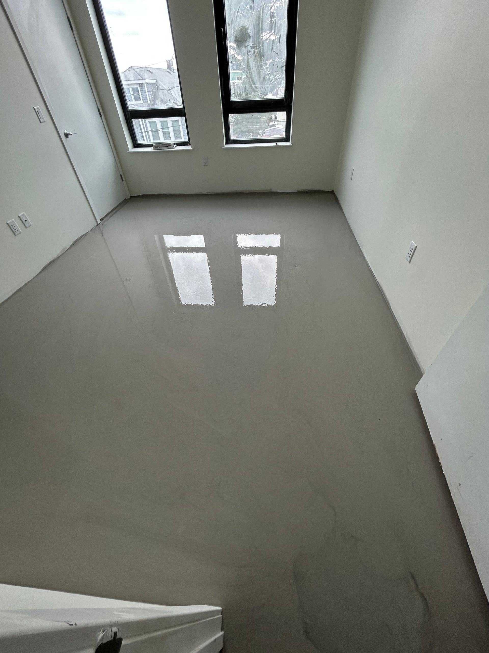 Partially tiled room with stacked materials, cords, and a tiled floor under construction