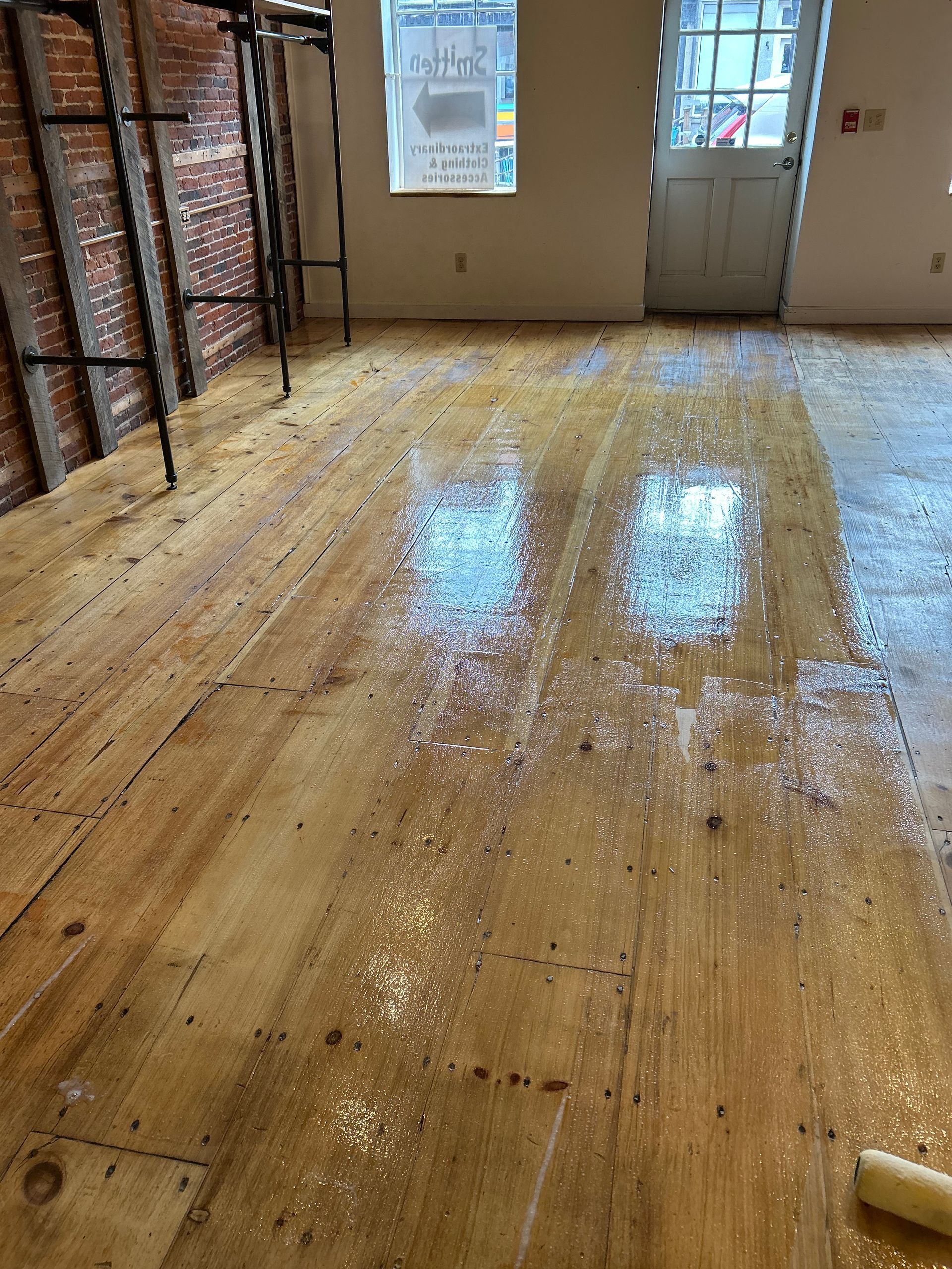 Shiny wooden floor in a room with stacked boxes on the left and a door and window at the back