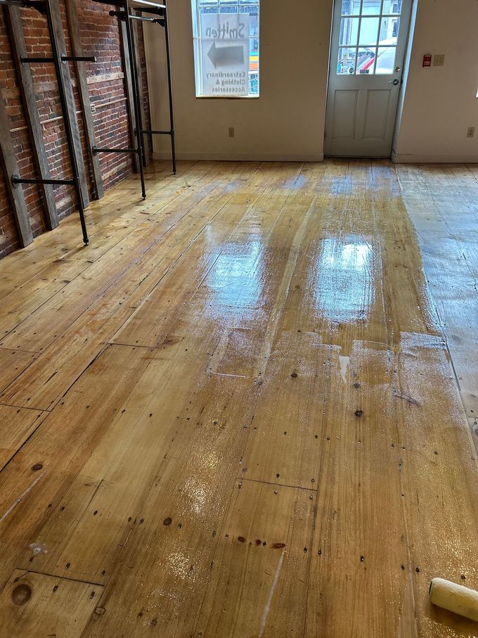Wooden floor in a room with stacked boxes along the left wall and a door at the back.