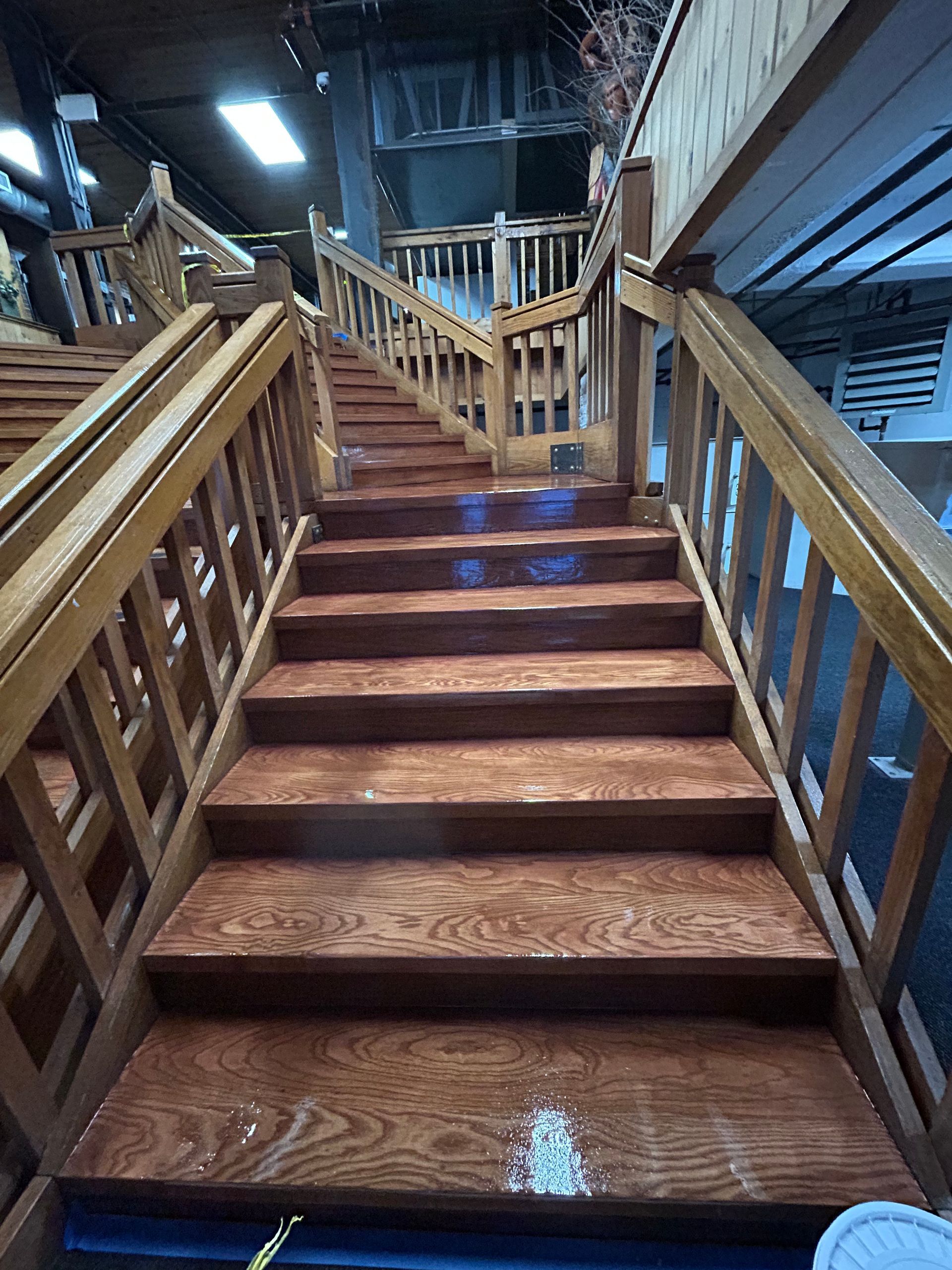 Wooden staircase with railings leading up to a dimly lit rustic interior.